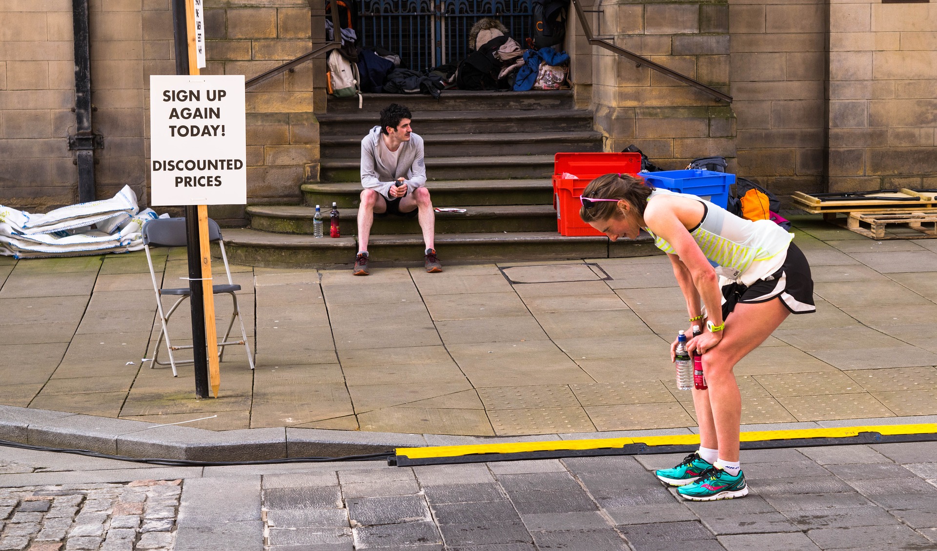 Marathon runner taking a breather with a sign saying 'Sign up again today! Discounted prices'